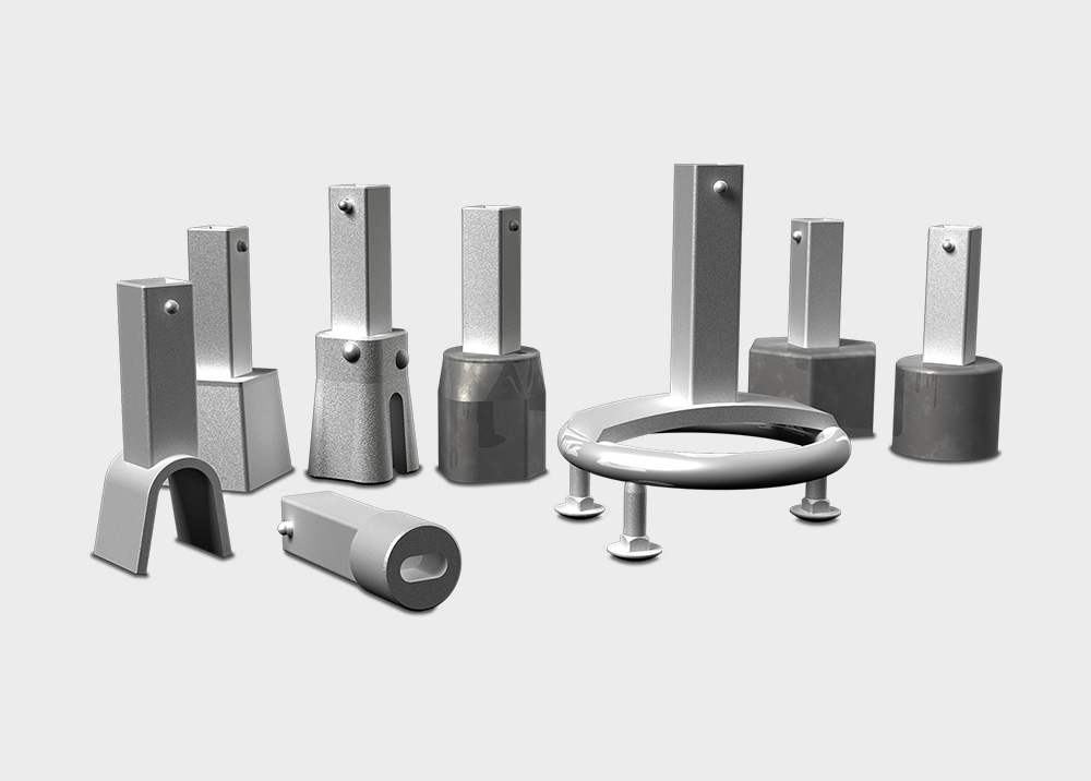 Mehrere silberne, metallische Stanzen und Werkzeugkomponenten vor einem grauen Hintergrund, in unterschiedlichen Formen und Größen angeordnet.